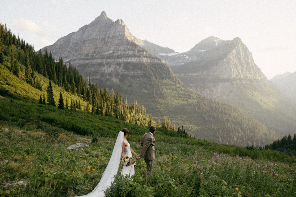 Elopement couple walk hand in hand in the mountains of Glacier National Park