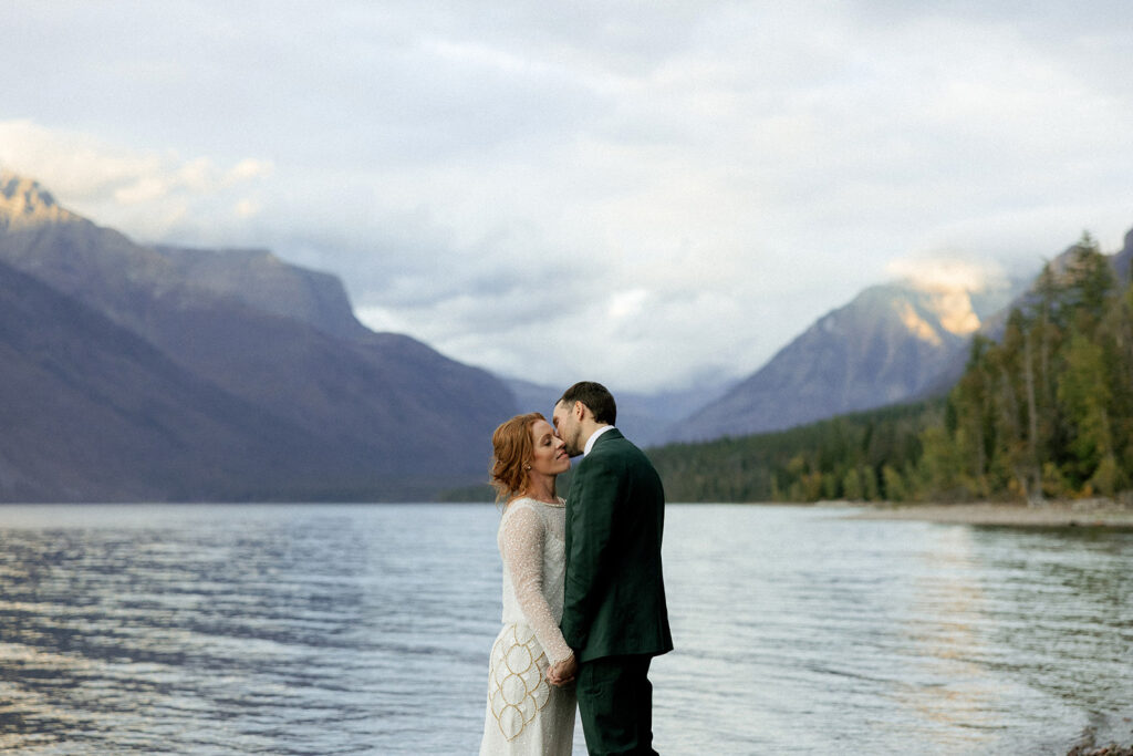 Bride and groom eloping in glacier national park along the shoreline of Lake McDonald