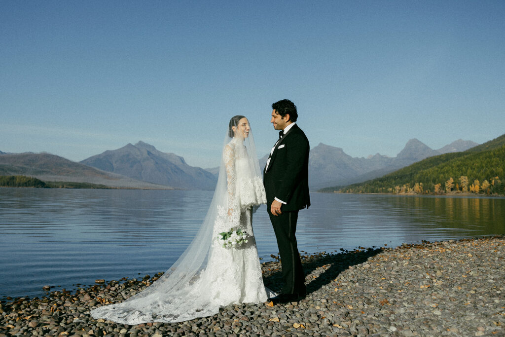 Bride and groom get married at Lake McDonald on a sunny day with a cathedral veil.