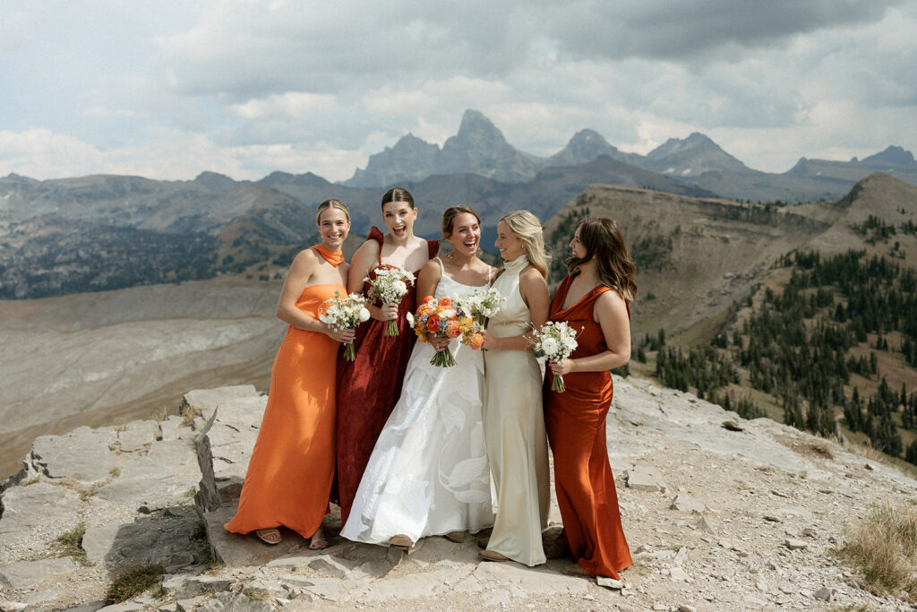 Bridesmaids at the top of Grand Targhee Resort with orange dresses
