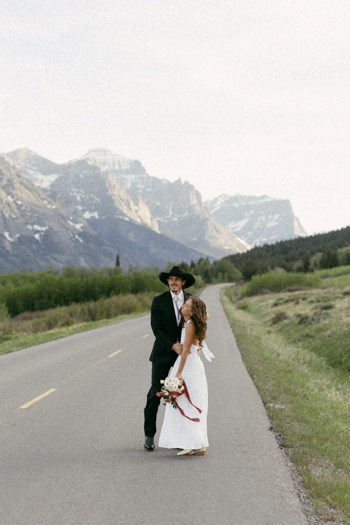 Bride and Groom running in the road during their Glacier National Park Elopement