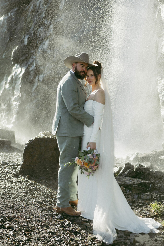 Bride and groom getting married in front of a waterfall in Glacier National Park