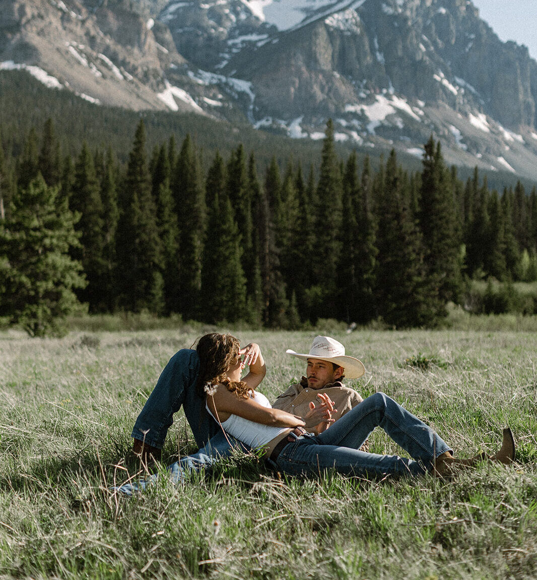 Couple lies in field at the Cut Bank Campground in Glacier National Park